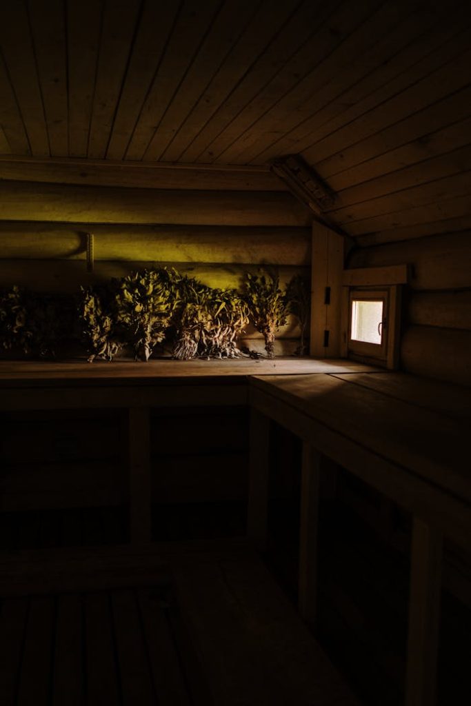 Warm and inviting sauna interior with dried herbs and soft lighting reflecting on wooden walls.