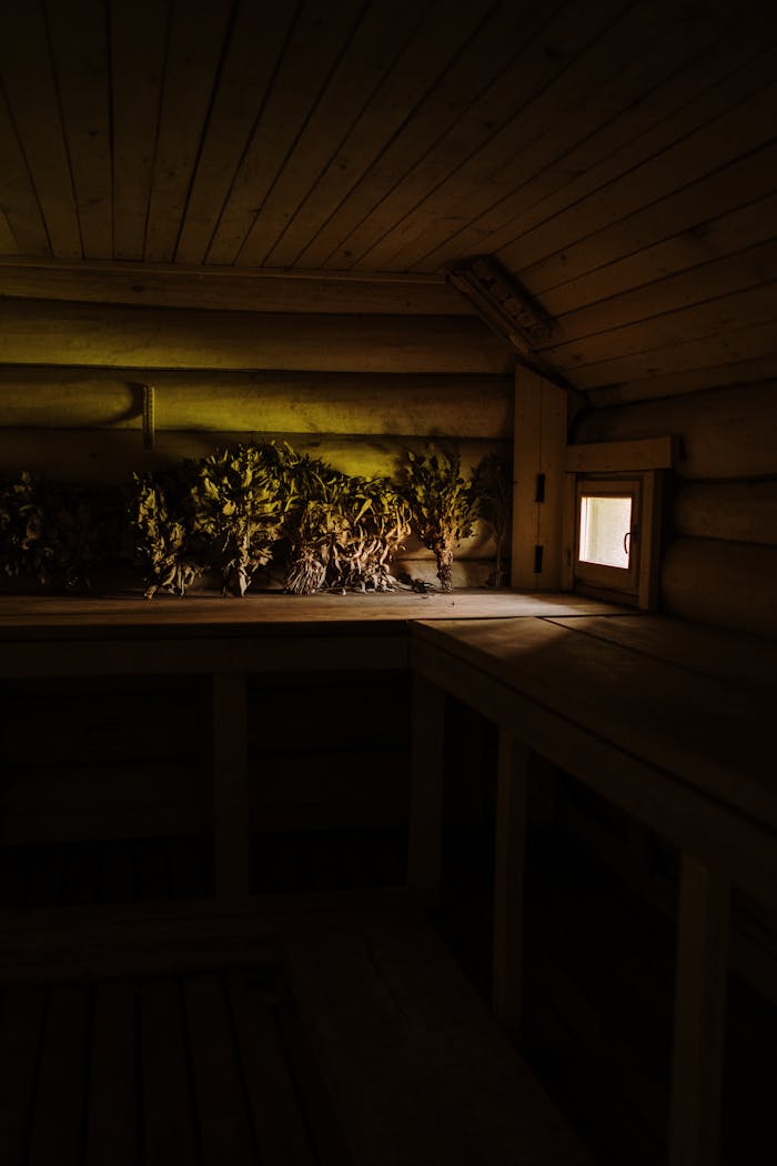Warm and inviting sauna interior with dried herbs and soft lighting reflecting on wooden walls.